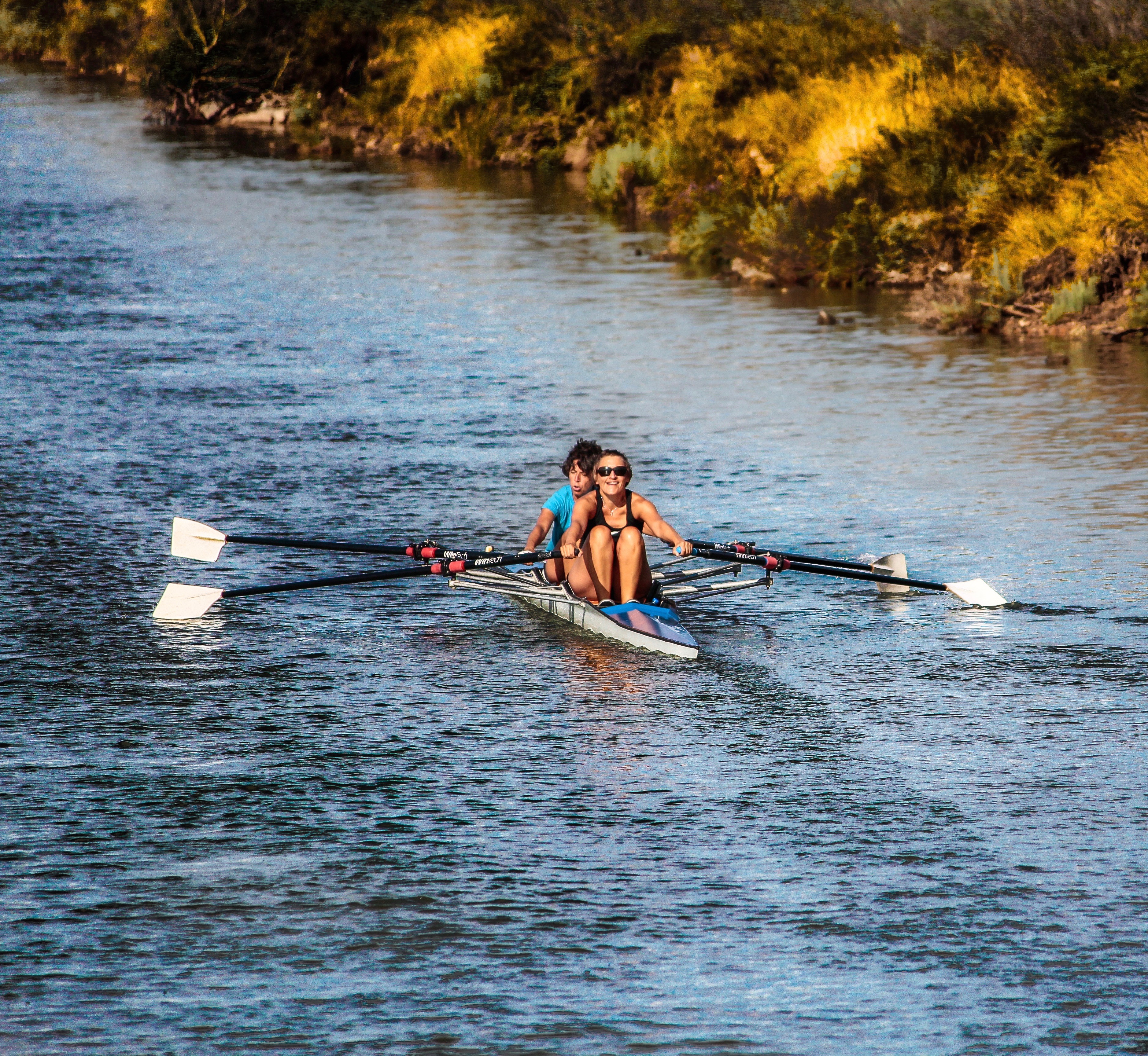 Two persons rowing in a skiff on a river