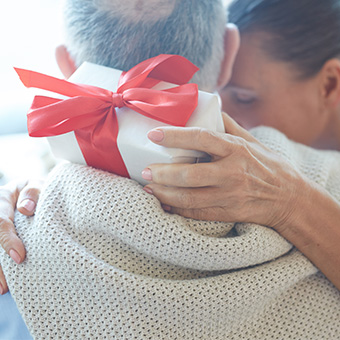 Älteres Ehepaar umarmt sich sich und macht ein Geschenk.